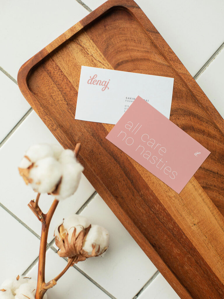 Denaj Beauty's business cards feature their signature soft pink on natural card stock - just one of the ways that the brand values are represented across this delicate brand by Yoco Studio.