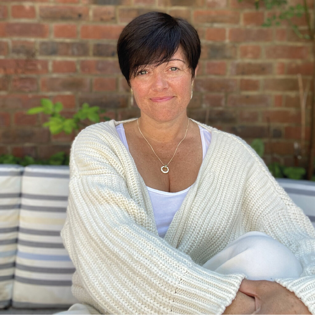 Amy Orsini (from Three Little Birds) sitting outside wearing a cream cardigan